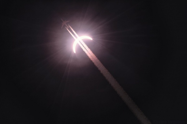 Một chiếc máy bay xẹt ngang bầu trời đang diễn ra nhật thực