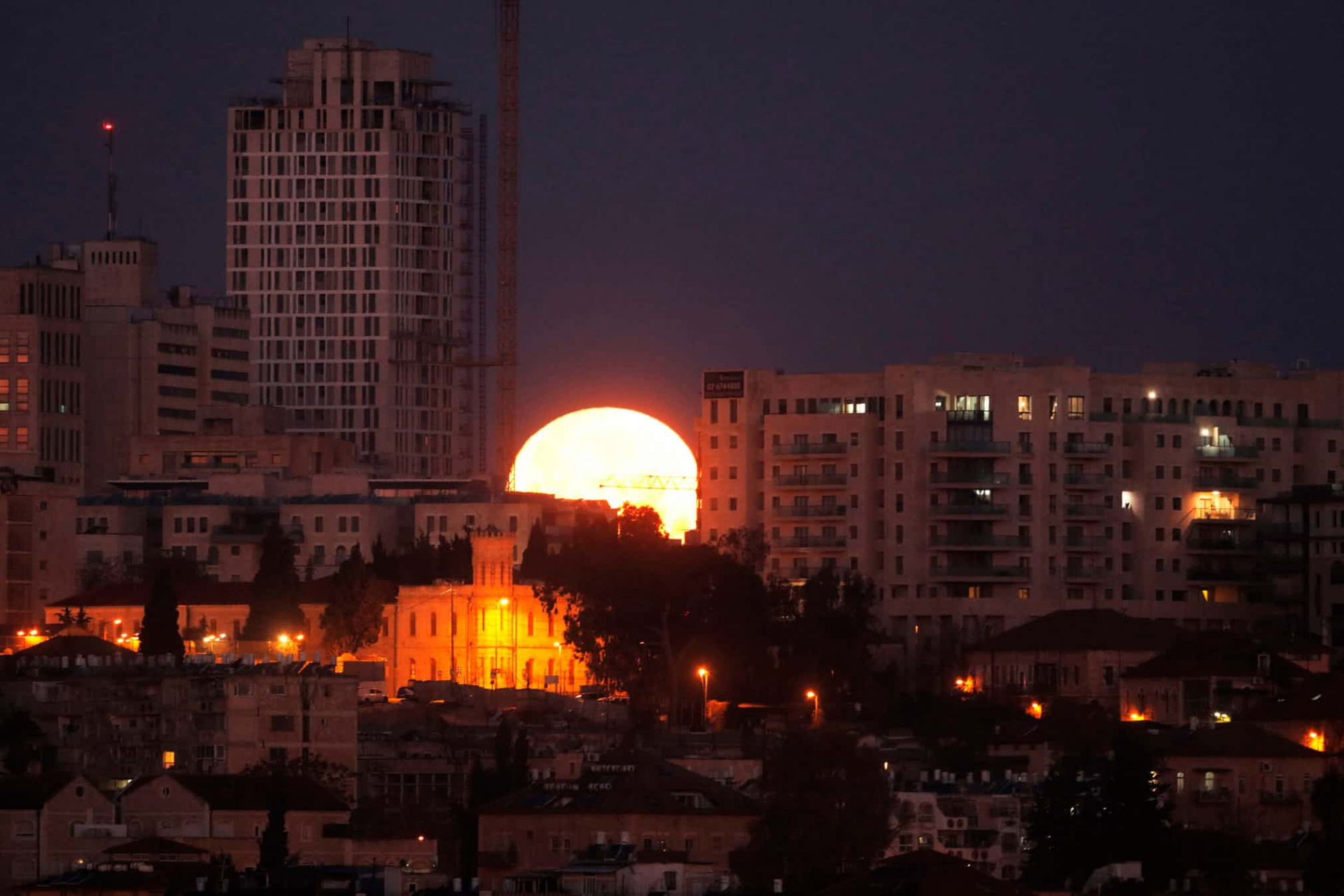 Siêu trăng giữa các tòa nhà ở Israel - Ảnh Menahem Kahana/AFP/Getty Images