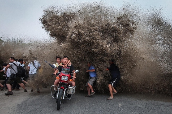 Người đi mô tô và đi bộ tập trung xem thuỷ triều lớn ở bờ sông Tiền Đường, Trung Quốc phải bỏ chạy khi con sóng đánh tràn bờ