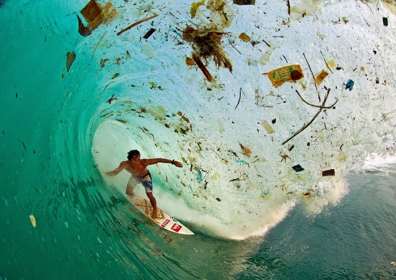 Một vận động viên lướt ván đang trổ tài dưới con sóng cuốn theo toàn rác tại vùng biển Java, Indonesia, vùng biển đông dân nhất thế giới. Nhiều khu vực trên thế giới có rất ít hoặc không có hạ tầng thu gom rác thải, do đó cư dân xả rác ra đường hoặc xuống nước, cuối cùng rác thải đều đổ ra biển.