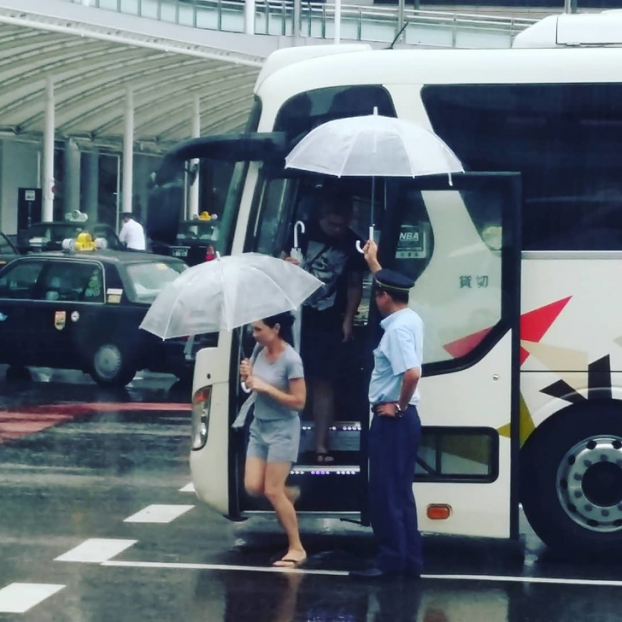   Tài xế xe buýt giữ ô phía trên để hành khách không bị ướt khi vừa xuống xe và chưa kịp mở ô  