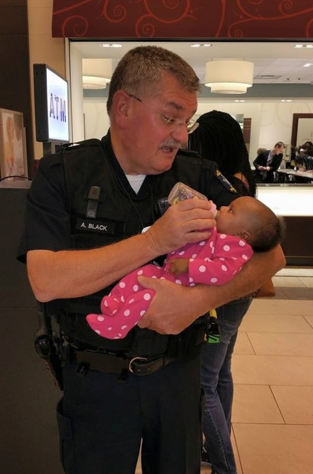   Các nhân viên y tế đang giúp nâng mẹ của em bé lên cáng và vị cảnh sát tốt bụng này đã nhận việc cho em bé ăn  