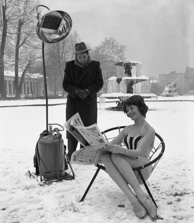   Một người mẫu đang quảng cáo tác dụng của chiếc đèn sưởi: Cô mặc bộ đồ mát mẻ trong khi mọi thứ xung quanh đóng băng (1960)  