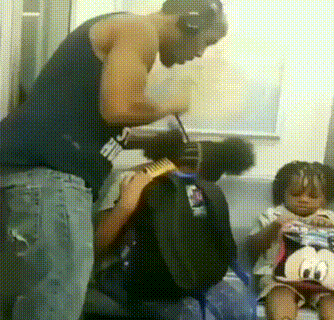  Một ông bố đang buộc tóc cho con trên tàu điện  