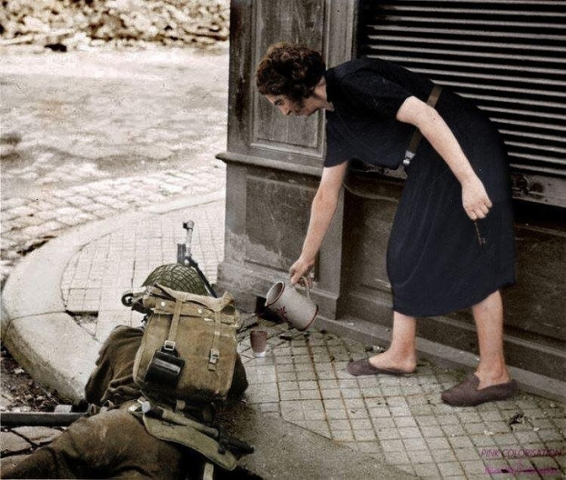   Một phụ nữ Pháp rót tách trà nóng cho người lính Anh chiến đấu ở Normandy, 1944  