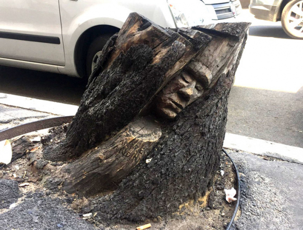   Khuôn mặt được khắc trên một gốc cây ở đường phố Rome  