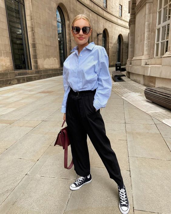 a blue striped shirt, black trousers, black Converse sneakers, a brown bag for a casual and comfy spring look