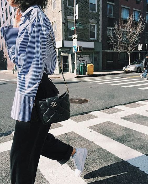 a blue stripe shirt, black trousers, white high top sneakers and a black bag for a classic and comfy spring look