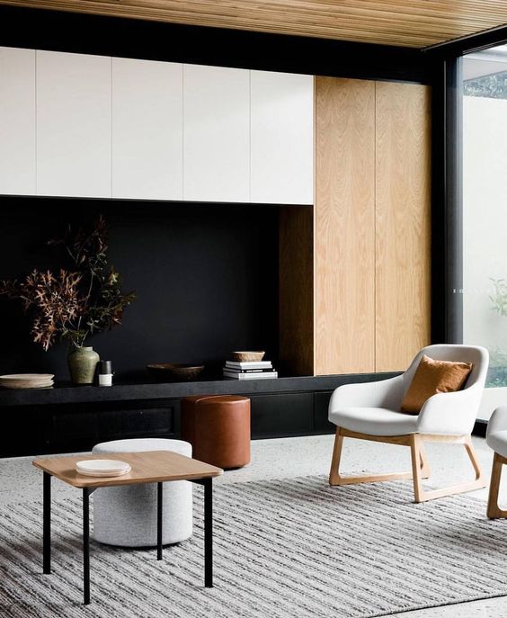 Một phòng khách đầy sự đối lập với ghế trắng, tường đen và đồ gỗ nhạt màu