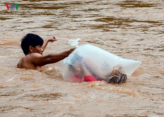   Hình ảnh người dân ở bản Huổi Hạ cho con chui vào túi nilon qua suối (Ảnh: VOV)  