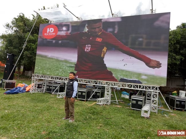   Một màn hình chiếu cỡ lớn do một công ty sự kiện tài trợ mới được dựng lên vào sáng nay tại sân bóng của thôn, sát nhà Quang Hải.  