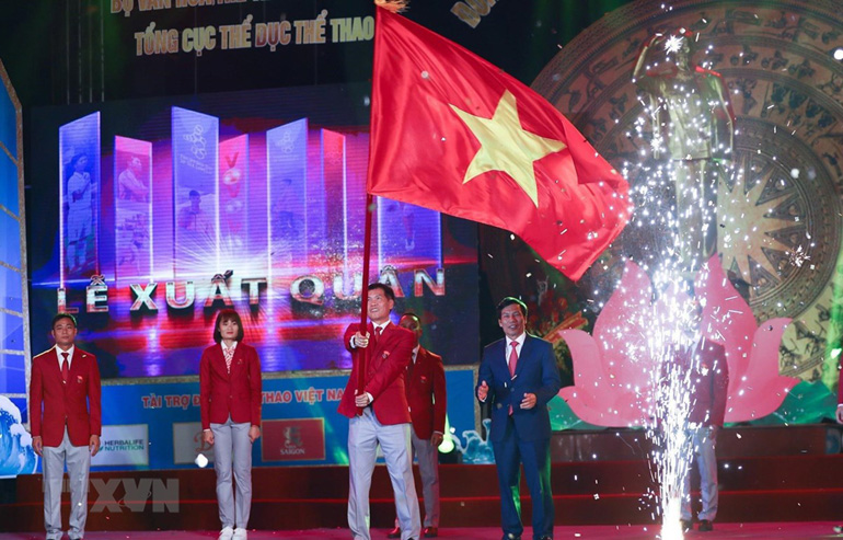 Ông Trần Đức Phấn, Phó Tổng cục trưởng Tổng cục Thể dục thể thao, Trưởng Đoàn thể thao Việt Nam tham dự SEA Games 30 phất cao lá quốc kỳ Việt Nam trong Lễ xuất quân. Ảnh: TTXVN