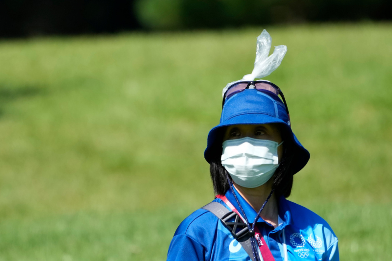 Một tình nguyện viên đứng với một túi nước đá trên đầu để chống chọi với thời tiết nóng bức trên sân Kasumigaseki Country Club. Ảnh: Michael Madrid-USA TODAY Sports