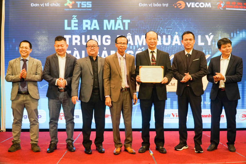 Ông Lương Hoàng Hưng (giữa) trao giấy chứng nhận hoạt động Trung Tâm Quản Lý Tài Sản Số TSS cho Hội đồng quản lý của TSS.