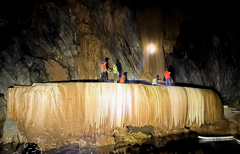 Một nhóm người khám phá hang động đã trèo lên thảm thạch nhũ để chụp ảnh.