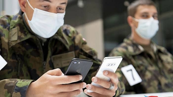 Các binh sĩ của quân đội Thụy Sĩ trong mặt nạ bảo vệ sử dụng các ứng dụng điện thoại thông minh của Google và Apple trong quá trình thử nghiệm theo dõi liên lạc. (Nguồn: Shutterstock)
