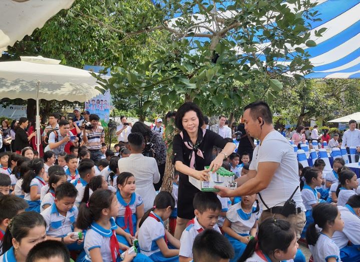 Các em học sinh trường Kim Đồng hồ hởi đón nhận những hộp sữa đầu tiên trong chương trình sữa học đường từ bà Bùi Thị Hương – Giám đốc Điều hành Vinamilk .