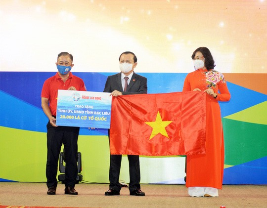 Bà Phan Thị Thắng, Phó Chủ tịch UBND TP HCM và ông Bùi Thanh Liêm (bìa trái), Phó Tổng Biên tập Báo Người Lao Động, trao cờ Tổ quốc và bảng tượng trưng 20.000 lá cờ cho ông Lê Tấn Cận, Phó Chủ tịch UBND tỉnh Bạc Liêu