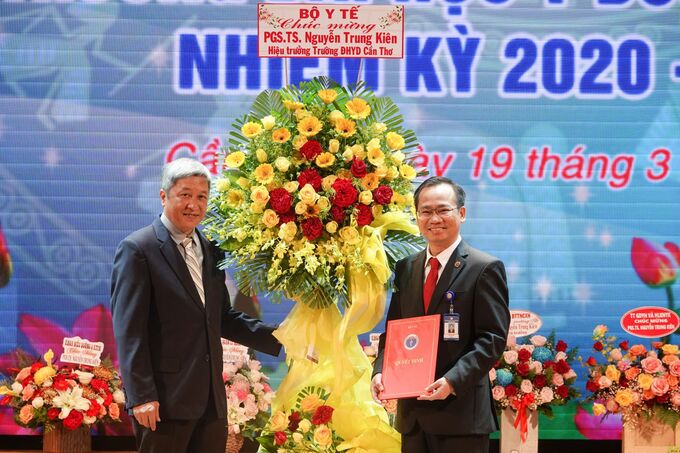 PGS-TS Nguyễn Trường Sơn, Thứ trưởng Bộ Y tế (bìa trái), trao quyết định và tặng hoa chúc mừng PGS-TS-BS Nguyễn Trung Kiên. Ảnh: Duy Khôi/ Báo Cần Thơ.