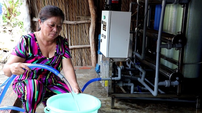 Cô Ngô Thị Hên lấy nước sạch – sản phẩm của hệ thống lọc nước để chuẩn bị bữa tối cho gia đình.