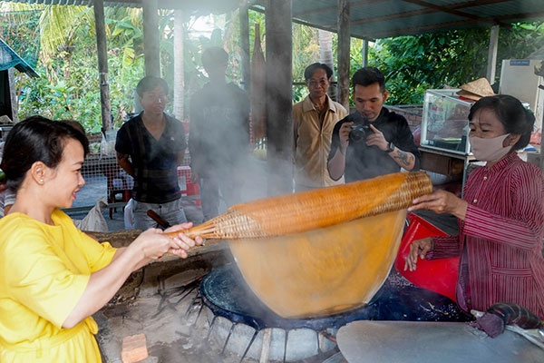 Du khách trải nghiệm tráng bánh và lấy ra để lên liếp phơi.