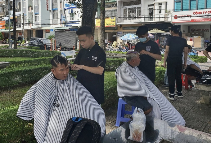 Các bạn trẻ của cửa tiệm D.A.T BarberShop đang cắt tóc cho người dân.