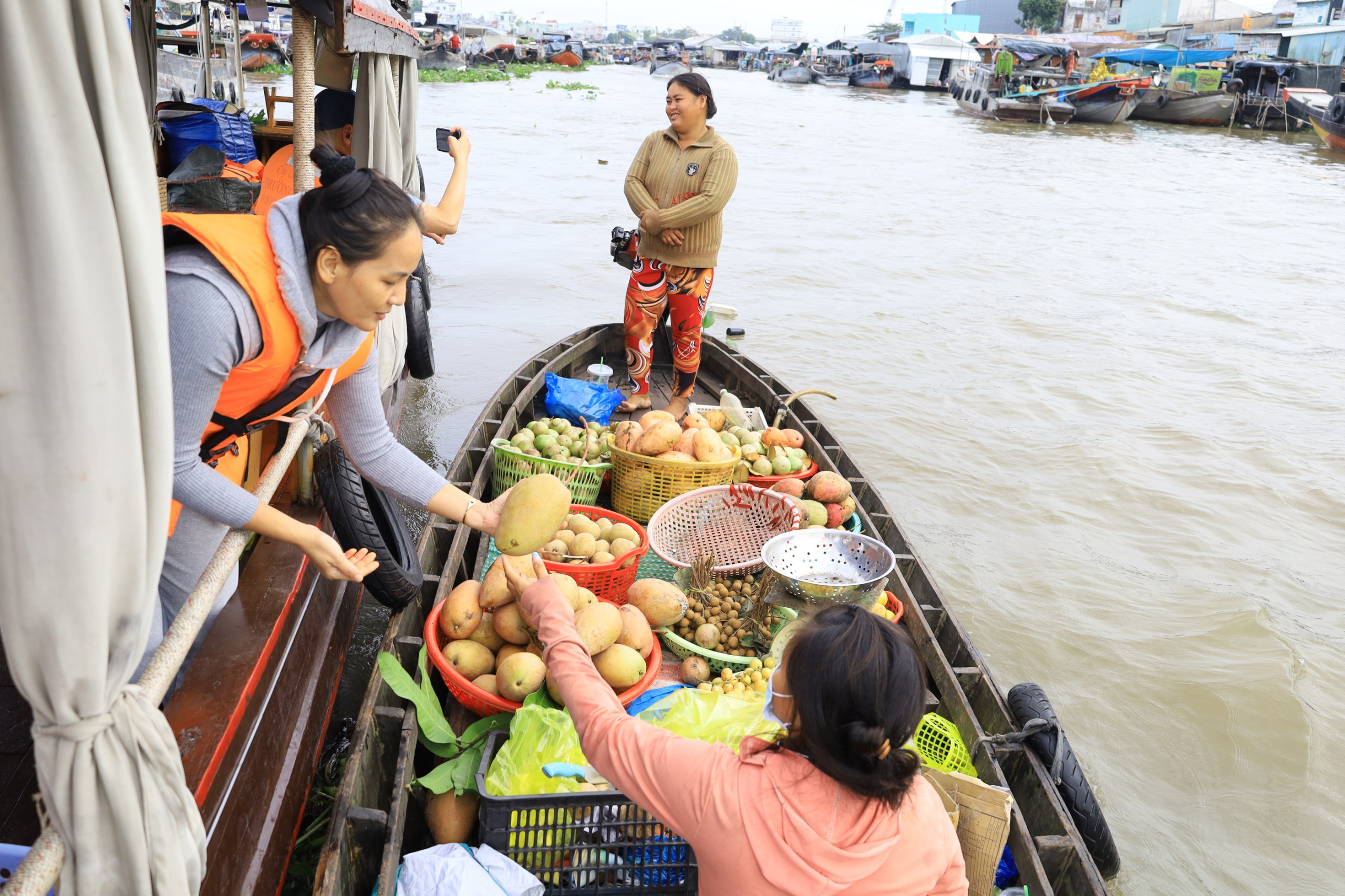 Du khách mua trái cây tại chợ nổi.