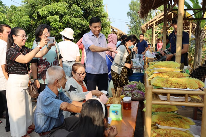 Chủ tịch Ủy ban nhân dân tỉnh Phạm Thiện Nghĩa tại gian hàng bánh xèo, một loại bánh dân gian của Nam bộ.
