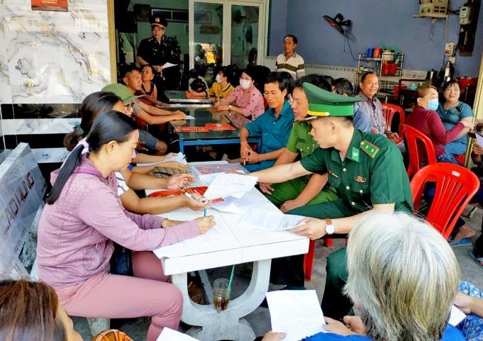 Cán bộ Đồn Biên phòng cửa khẩu Vĩnh Hội Đông vận động, hướng dẫn người dân ký cam kết phòng, chống tác hại của thuốc lá. Ảnh: Chiến Khu.