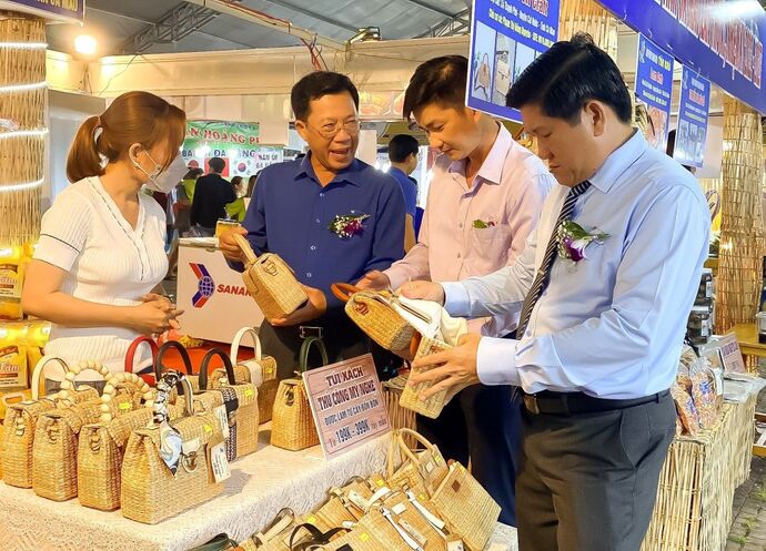 Phó Chủ tịch UBND tỉnh Lê Văn Sử (bìa phải) tham quan gian hàng trưng bày các sản phẩm từ cây bồn bồn của chị Nguyên được tại hội chợ, không gian khởi nghiệp.