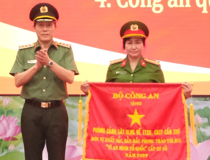 Đại tá Nguyễn Hồng Trinh, Trưởng Phòng Cảnh sát QLHC về TTXH, Công an TP Cần Thơ (phải) nhận Cờ thi đua Đơn vị xuất sắc, dẫn đầu phong trào thi đua Vì an ninh Tổ quốc cấp cơ sở năm 2022 do lãnh đạo Bộ Công an tặng.
