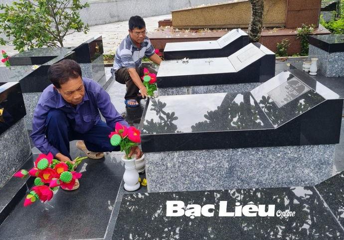 Ông Lê Hoàng Giang (bên trái) cùng đồng nghiệp chỉnh trang các phần mộ liệt sĩ. Ảnh: T.Q