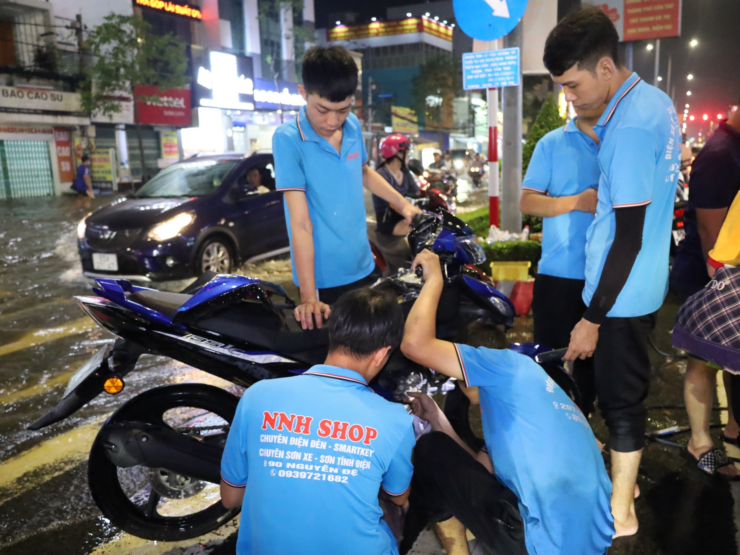 Nhân viên một cơ sở sửa chữa xe gắn máy tham gia hỗ trợ người dân sửa xe miễn phí.