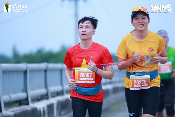 Anh Hữu Cảnh và người dẫn đường Trương Việt Mỹ (Phó Chủ Nhiệm CLB Chạy bộ Cà Mau - CMRC) nối với nhau bằng một sợi dây khi chạy