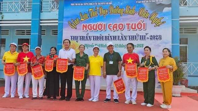 Bà Lê Hồng Xuân - Chủ nhiệm CLB dưỡng sinh thị trấn Thới Bình trao cờ lưu niệm cho các đơn vị