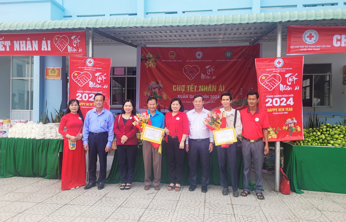 Ông Huỳnh Văn Thôn (áo xanh dương) chụp ảnh cùng các đại biểu tại gian hàng chợ 'Tết nhân ái'