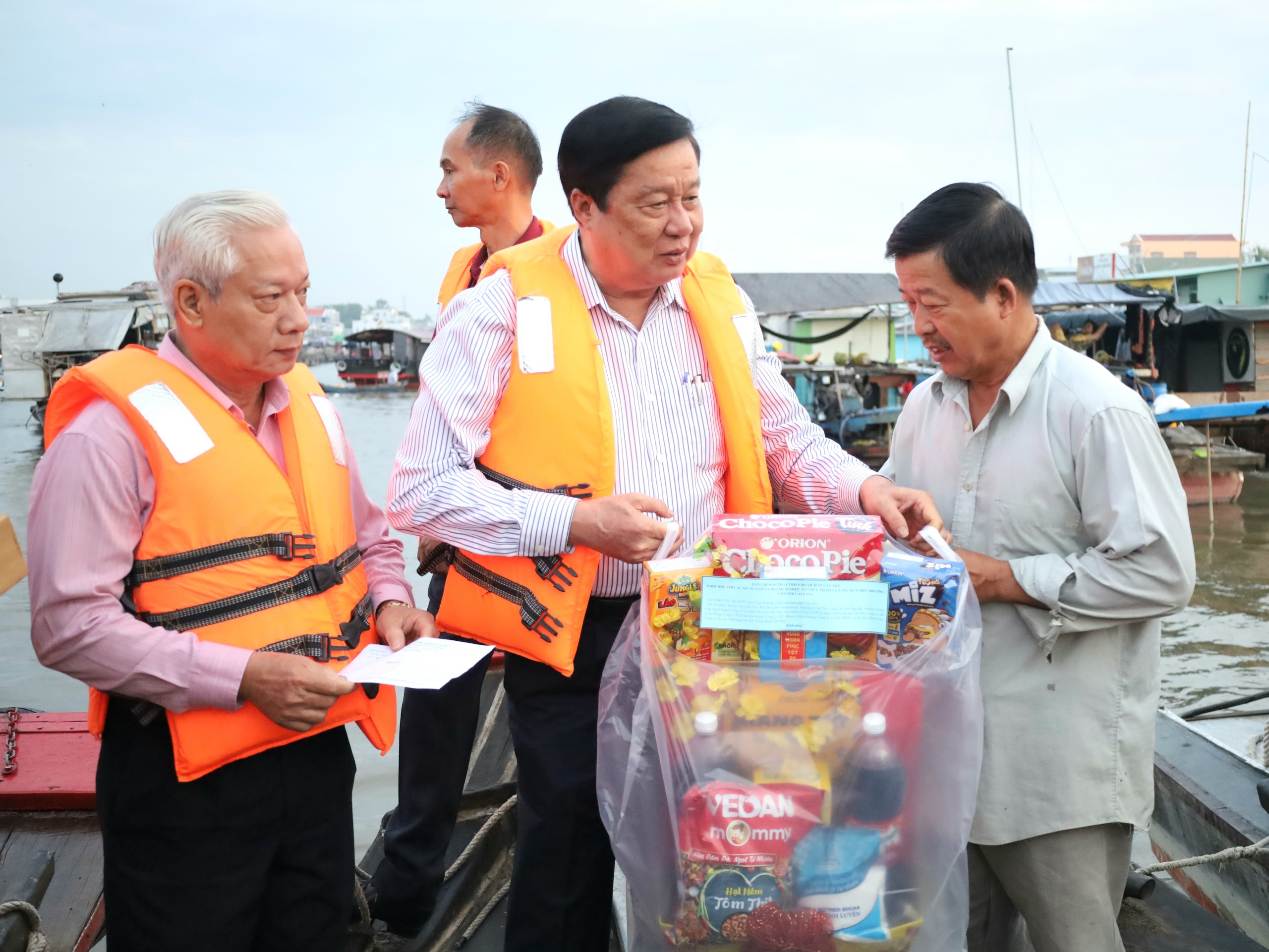 Ông Phạm Văn Hiểu (đứng giữa) - Phó Bí thư Thường trực Thành ủy, Chủ tịch HĐND TP. Cần Thơ và ông Mai Thanh Dân - nguyên Trưởng Ban Tổ chức Thành ủy Cần Thơ trao tặng quà cho thương hồ tại Chợ nổi Cái Răng.