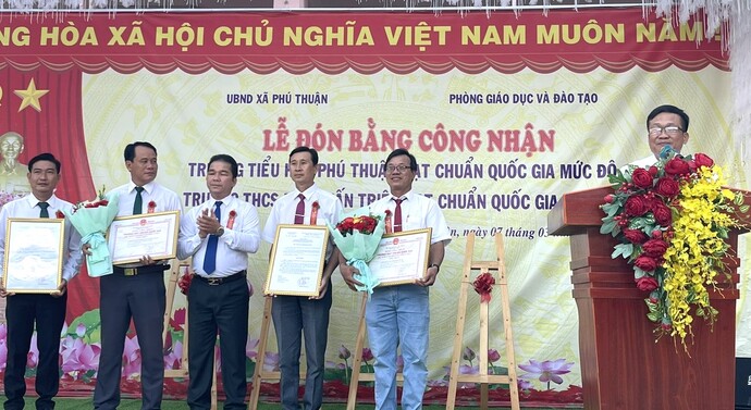 Ông Trương Hoàng Khải - Ủy viên BTVHU, Phó chủ tịch UBND huyện trao quyết định và bằng công nhận cho trường Tiểu học Phú Thuận đạt chuẩn quốc gia mức độ 1; trường Trung học Cơ sở Đặng Tấn Triệu đạt chuẩn quốc gia mức độ 2 .