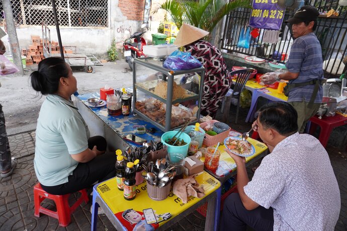 Sở dĩ người dân địa phương gọi là cơm tấm bà Cụ hay cơm tấm Thủ Khoa Huân là vì ngày trước, trên khúc đường Thủ Khoa Huân có một bà lão tóc bạc trắng bán cơm nhưng không có bảng hiệu. Ngày qua ngày được nhiều người biết tới, từ đó có thêm chi nhánh cơm bà Cụ xuất hiện tại bờ hồ Huỳnh Cương, do gia đình của bà đứng bán từ 6 giờ - 9 giờ sáng mỗi ngày.