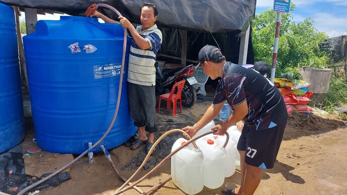 Ông Triệu Văn Út (áo thun sọc xanh trắng) đang bơm nước vào bồn chứa để bà con lấy về sử dụng.