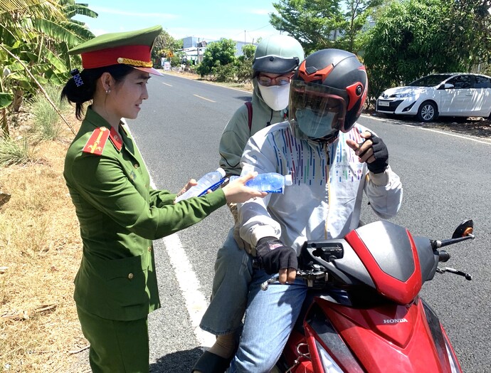 Lực lượng Công an huyện Thới Bình đang tặng nước và khăn lạnh miễn phí cho người dân về quê nghĩ lễ.