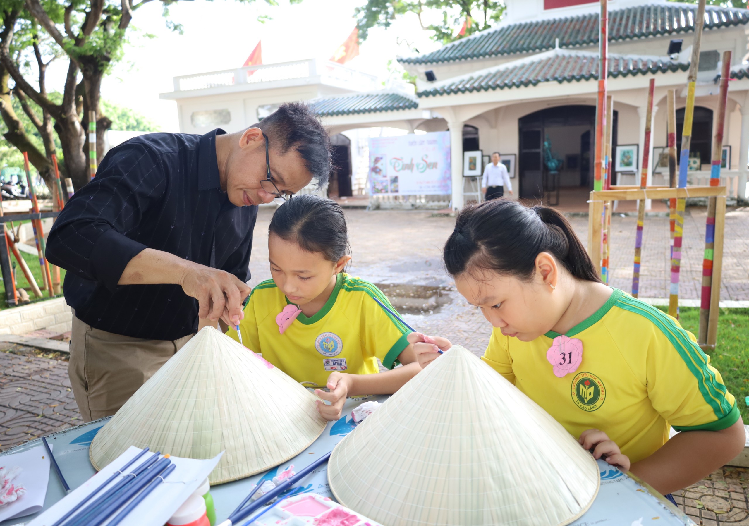 Các em học sinh tham gia trải nghiệm tô màu trên nón lá.