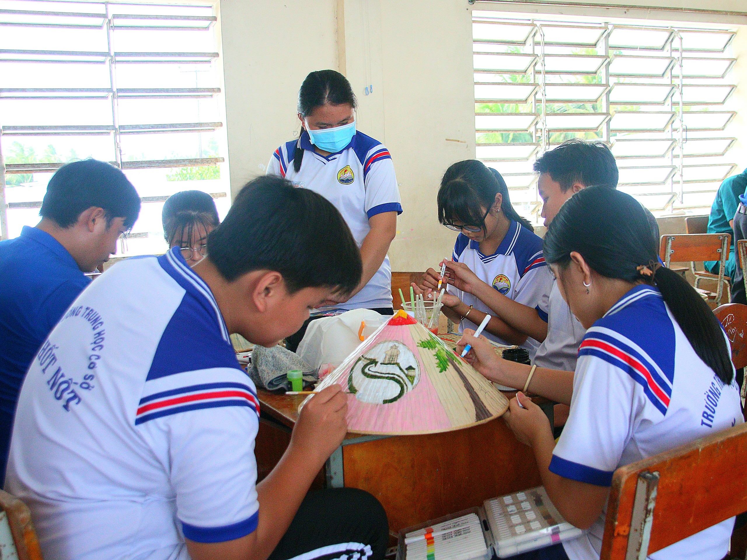 Các em học sinh tham gi dự thi vẽ trang trí nón lá.