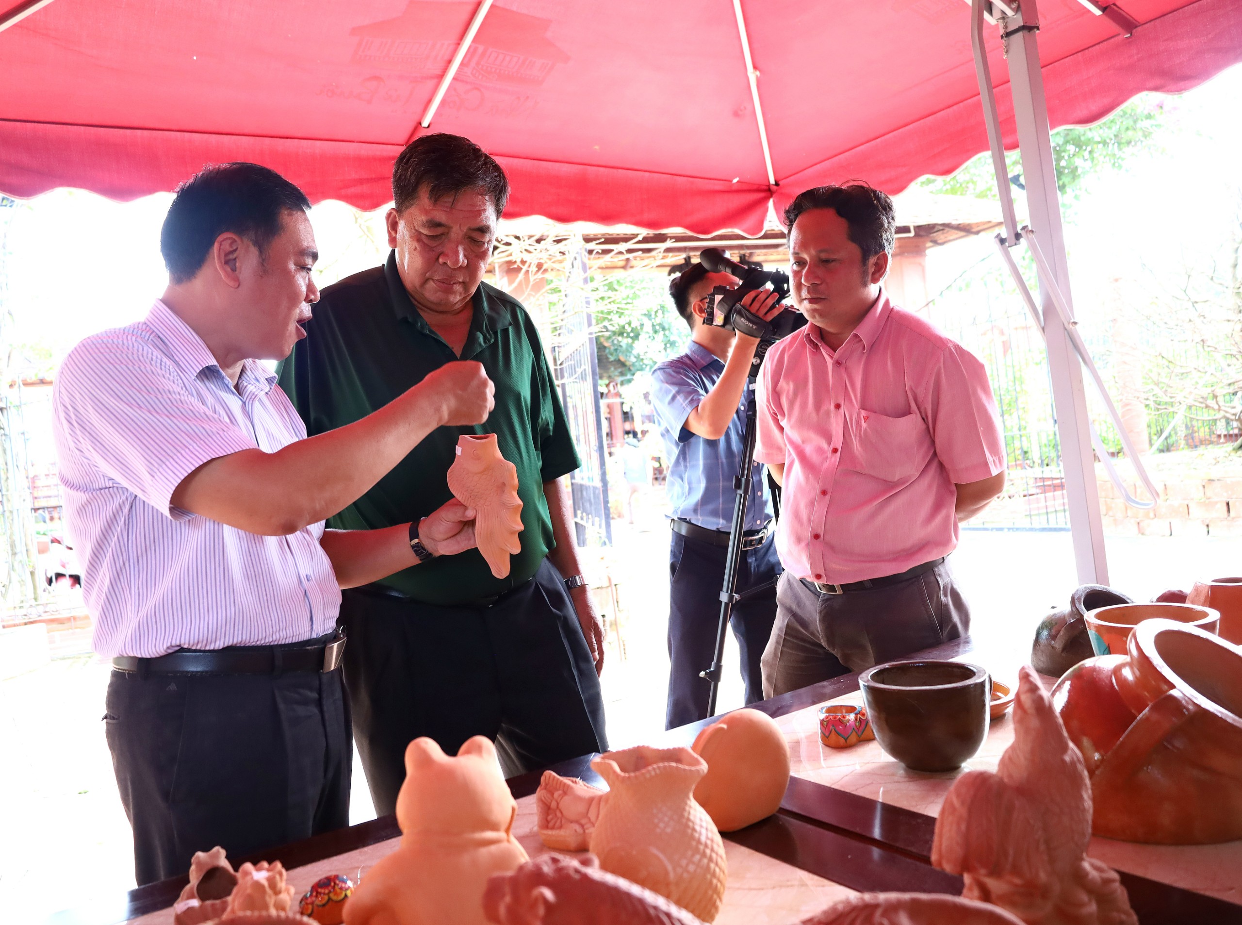 Ông Nguyễn Văn Buôi (đứng giữa) giới thiệu các sản phẩm được làm từ Gốm đỏ.