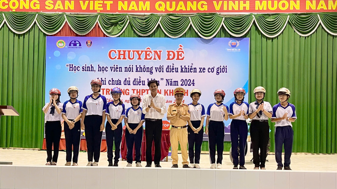 Ông Mai Minh Ngoan - Chánh văn phòng Ban ATGT TP Cần Thơ và cán bộ phòng CSGT tặng nón bảo hiểm cho học sinh.