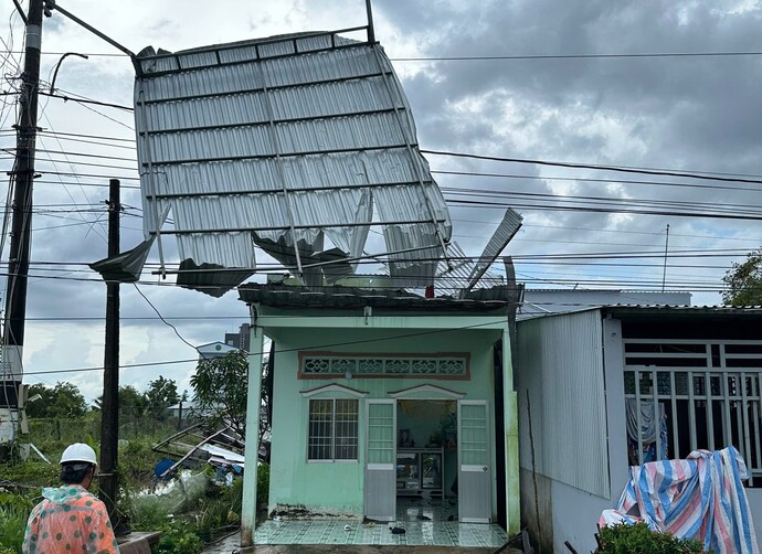 Lốc xoáy cuốn bay mái tôn lên không trung và vướng vào dây điện.