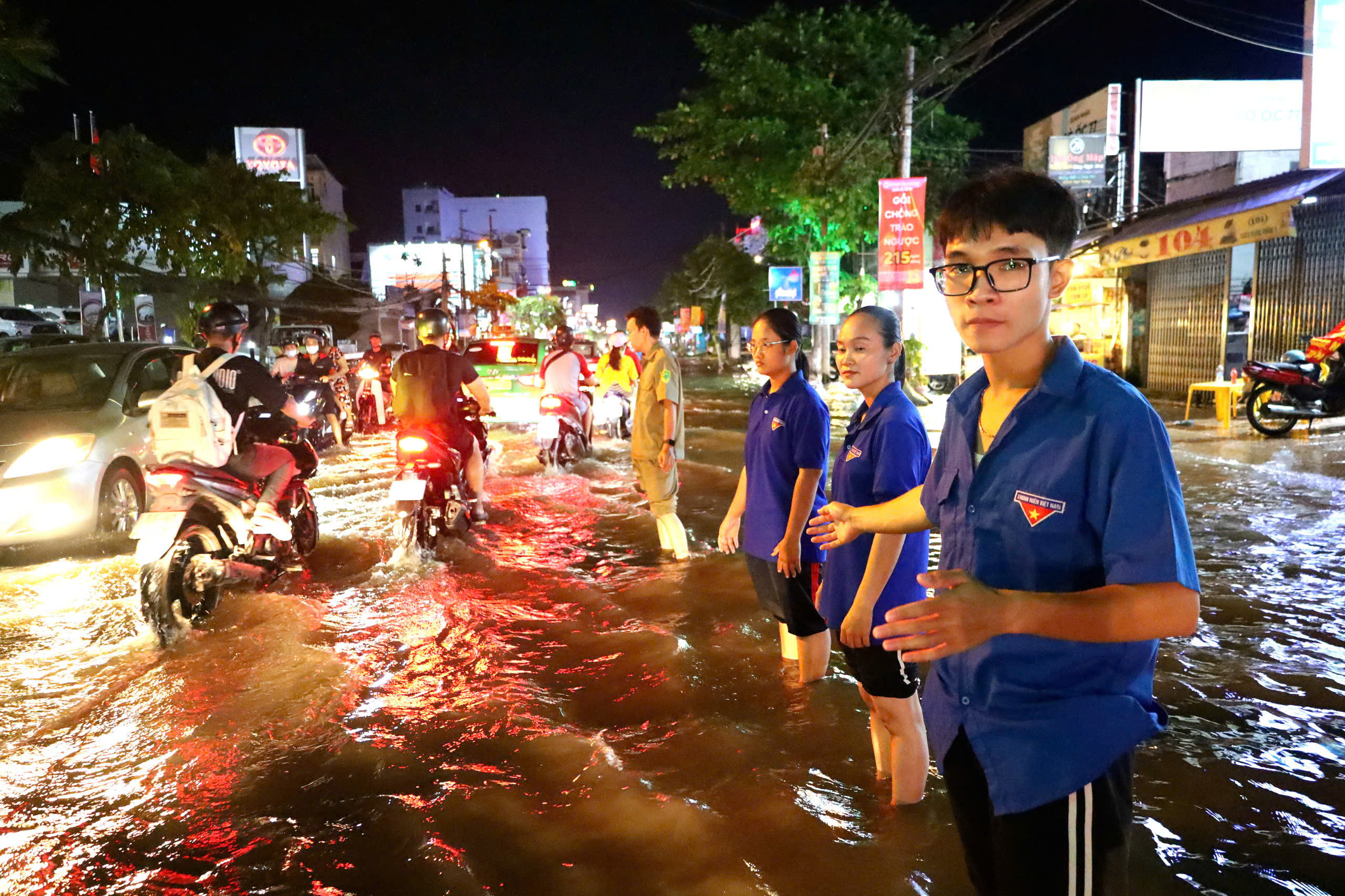 Lực lượng Đoàn viên phường Cái Khế, quận Ninh Kiều hỗ trợ phân luồng để xe honda không đi vào đoạn ngập sâu trên đường Cách mạng tháng 8.