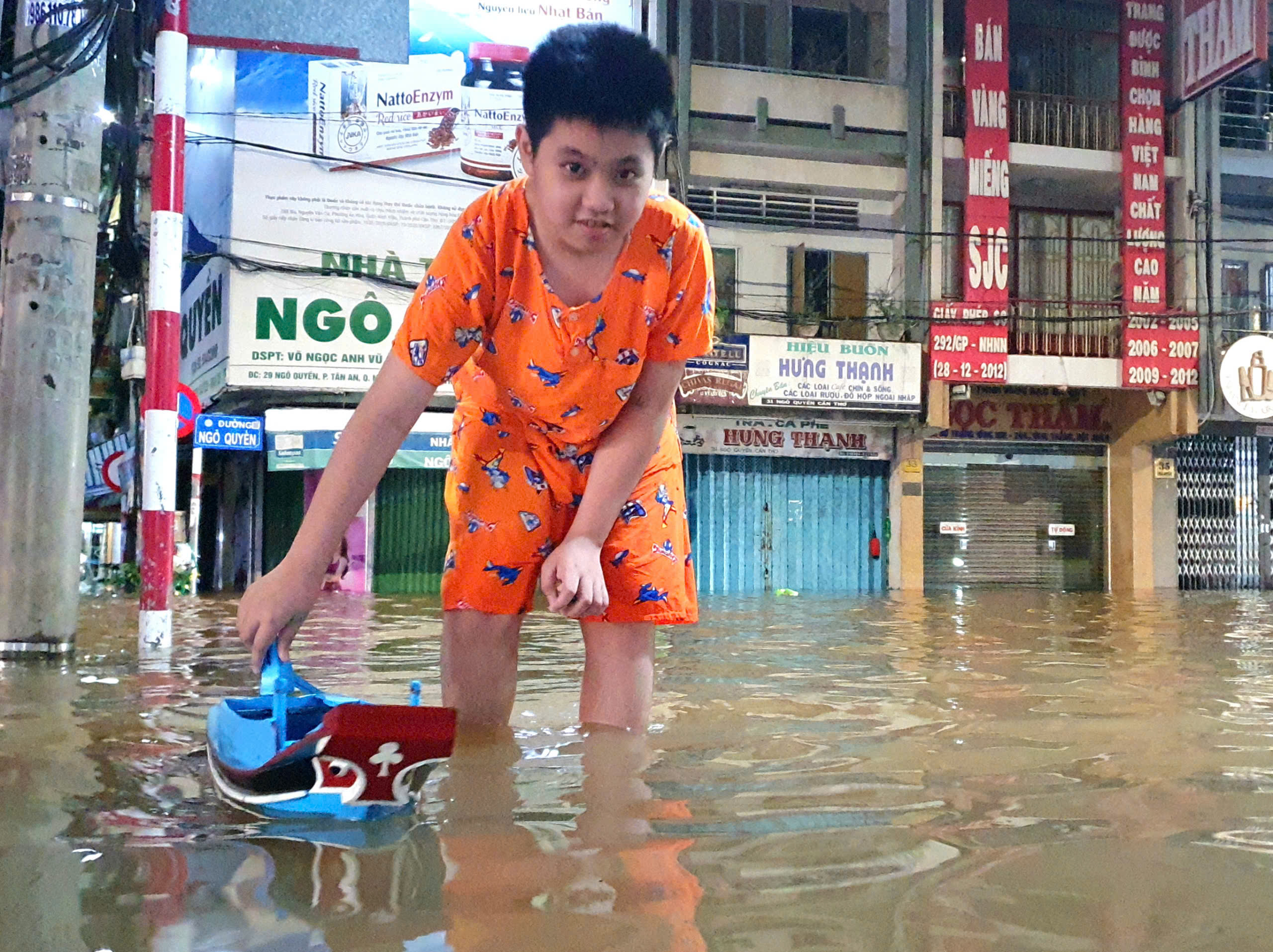 Một em nhỏ chơi mô hình vỏ lãi trước sân nhà.