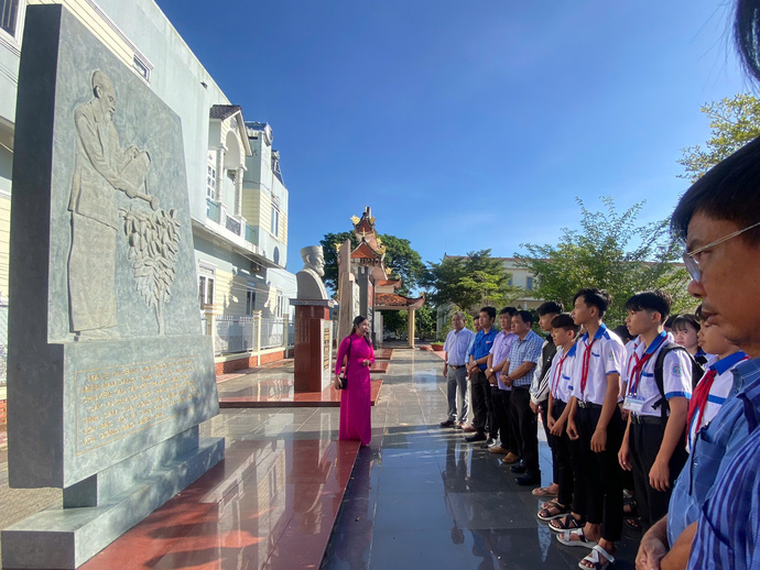 Lãnh đạo và học sinh nghe thuyết minh về lịch sử cây vú sữa niềm Nam với Bác Hồ.