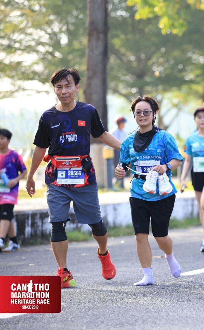 Anh Ngô Thanh Toàn cùng con gái Ngô Võ Trâm Anh, khi cô phải xách giày vì chấn thương chân, vẫn kiên trì bước những bước cuối để cùng nhau về đích.